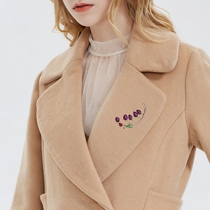 Elegant grape cluster brooch with purple gems and red ladybug on camel wool coat lapel