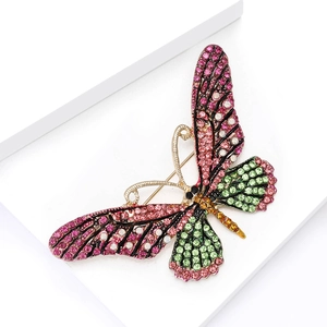 Macro shot of colorful butterfly brooch with pink and green rhinestones on white stairs