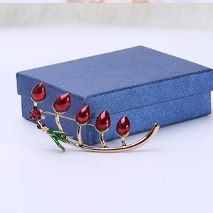 Detailed close-up of a tulip brooch with red enamel buds and a ladybug on a jewelry box