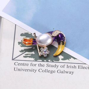 Detail of creative parrot brooch with pearl and colorful enamel on book pages