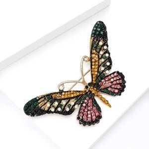 Macro detail of luxury butterfly brooch featuring colorful rhinestones on gold metal