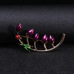 Detail of leaf beetle brooch with purple beads and golden stem on black leather