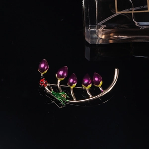 Detail of purple flower bud brooch with golden alloy stem and tiny red ladybug accent