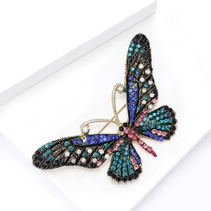 Elegant butterfly brooch with colorful rhinestones on a white geometric display stand
