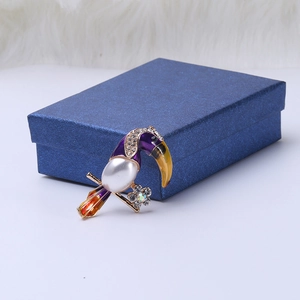 Detailed view of toucan brooch featuring vibrant enamel, crystals, and a large drop pearl