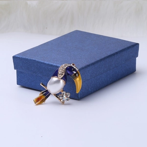 Detail view of toucan brooch featuring large pearl body and colorful enamel on jewelry box