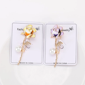 Detailed macro of handmade floral brooches with colorful enamel finish and pearl accents