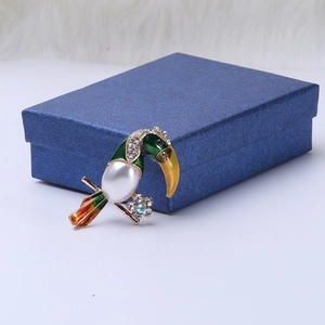 Detailed close-up of tropical toucan brooch with green enamel and pearl inlay on a jewelry box