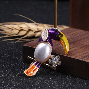 Macro shot of toucan brooch featuring white pearl, purple enamel, and sparkling crystals