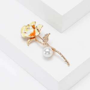 Macro view of handmade enamel rose brooch with zircon leaves and a white pearl drop