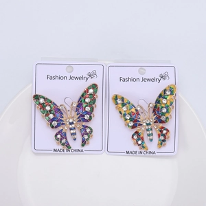 Macro shot of colorful enamel butterfly brooches with rhinestones on a white plate