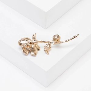 Detailed back view of golden flower brooch showing secure pin fastener and metal texture