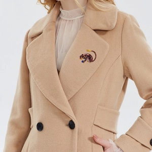 Chic sloth animal brooch with blue bead pinned on a beige coat lapel for elegant styling