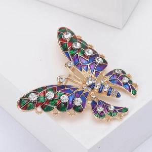 Macro shot of colorful enamel butterfly brooch with sparkling crystals on white stand