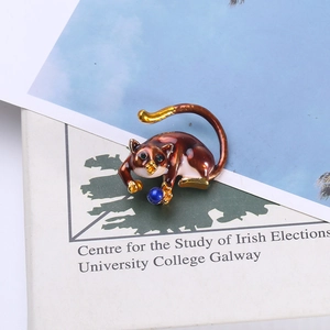 Detail view of cat brooch with brown enamel, blue bead and green crystal eyes
