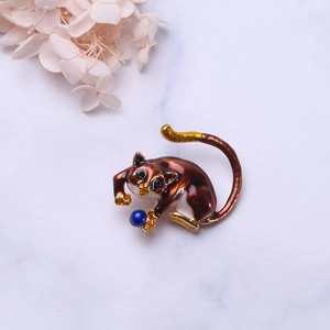 Detail of sloth animal brooch featuring red enamel, gold plating and blue pearl bead decoration