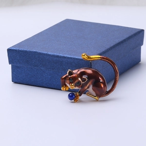 Detail of sloth enamel brooch with reddish-brown finish and blue bead accent