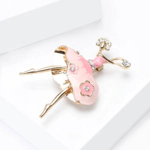 Detailed close-up of a golden ballerina brooch with pink enamel and sparkling rhinestones