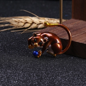 Detailed view of an alloy sloth brooch with enamel finish and a blue bead on a wooden stand