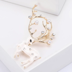 Détails d'une broche élan en émail avec perles blanches et strass brillants sur bois dorés