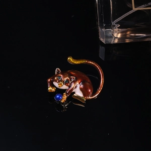 Detailed macro shot of a glossy brown enamel cat brooch with green gem eyes and gold accents