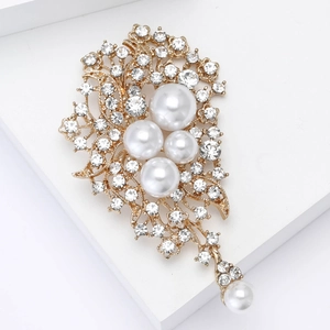 Détail d'une broche fleur vintage dorée ornée de strass brillants et de perles blanches