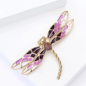 Gros plan d'une broche libellule avec ailes en émail violet et détails en diamants