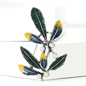 Dettaglio di spilla a foglia con cristalli verdi, smalto blu e perle bianche