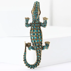 Fashionable crocodile brooch pin with sparkling blue rhinestones on a white stand