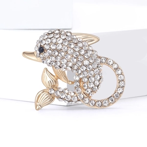 Macro view of a gold dolphin brooch with sparkling crystal rhinestones and black gem eyes