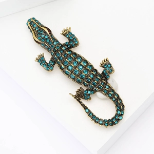 Vintage gold alloy crocodile brooch with blue rhinestones on a white geometric stage