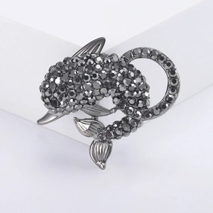 Sparkling dolphin brooch with dark grey rhinestones on minimalist white pedestal