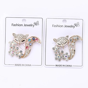 Vue détaillée de deux broches renard dorées ornées de strass brillants sur carton blanc
