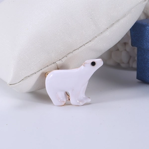 Detail view of polar bear enamel brooch with gold-tone edges on a textured surface