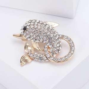 Macro shot of handcrafted gold dolphin brooch with sparkling white crystals and black eyes