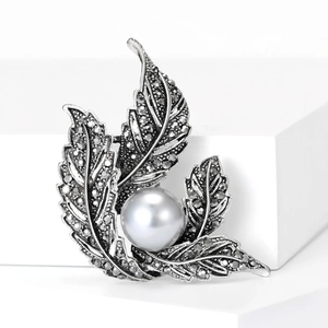 Close-up of vintage leaf brooch with pavé stones and a large grey satin pearl inlay