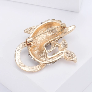 Macro detail of the golden dolphin brooch back showing the rotating safety clasp and alloy finish