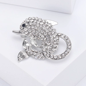 Close-up of dolphin brooch with sparkling white crystals and black gem eye on silver base
