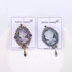 Detail of vintage cameo brooches with rhinestones and teardrop pendants in two colors