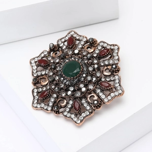 Baroque vintage alloy brooch with a large green gemstone and multicolor rhinestones