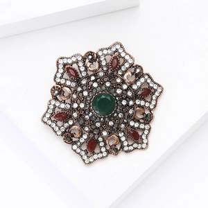 Baroque vintage brooch with green center crystal and rhinestone clusters on bronze base