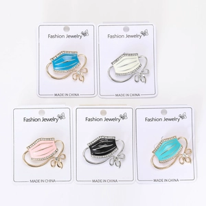 Macro detail of enamel face mask brooches with rhinestones in five various colors