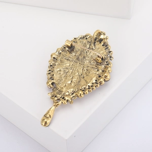 Detailed back view of vintage gold brooch with safety pin and water-drop pendant