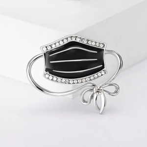 Detail of enamel mask brooch with silver frame and sparkling rhinestone bow accents
