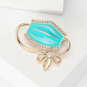 Close-up of blue enamel mask brooch with gold bow and sparkling crystal details