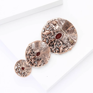 Macro shot of vintage bronze brooch with leaf textures and deep red gemstone accents