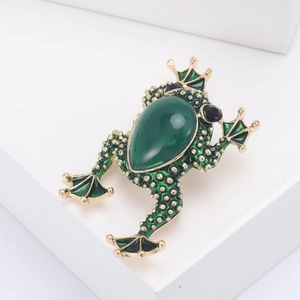 Detail of vintage green frog brooch with emerald teardrop stone and gold-toned texture