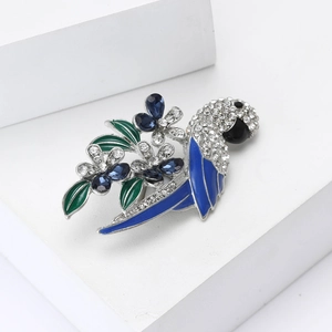 Elegant silver parrot brooch with blue crystals and green enamel on a white podium