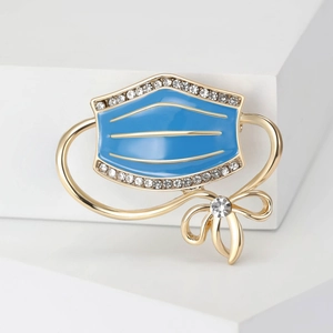 Detailed macro of gold-plated enamel medical mask brooch with sparkling rhinestones