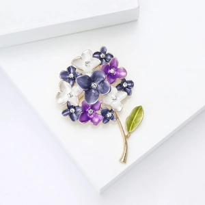Macro detail of enamel hydrangea brooch with purple rhinestones on a golden base
